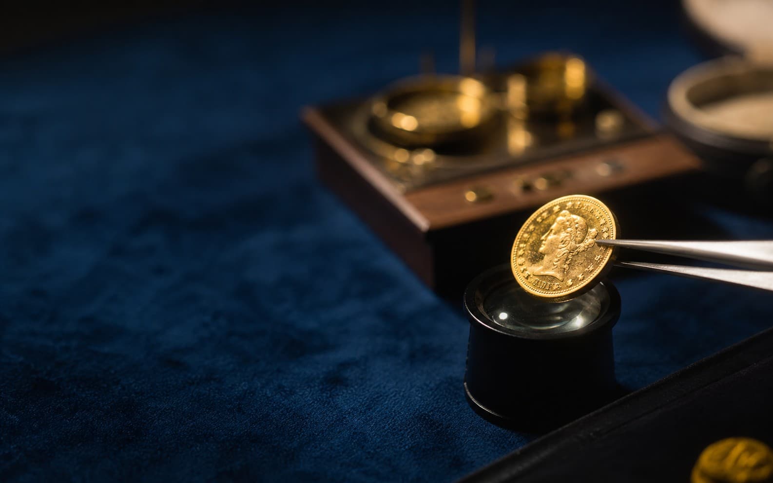Pièce en or examinée à la loupe sur velours bleu